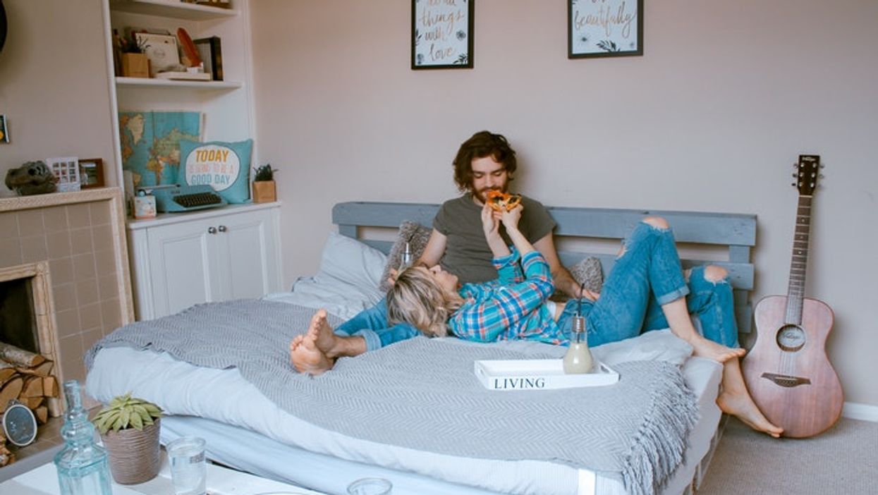 Couple eating pizza in bed.