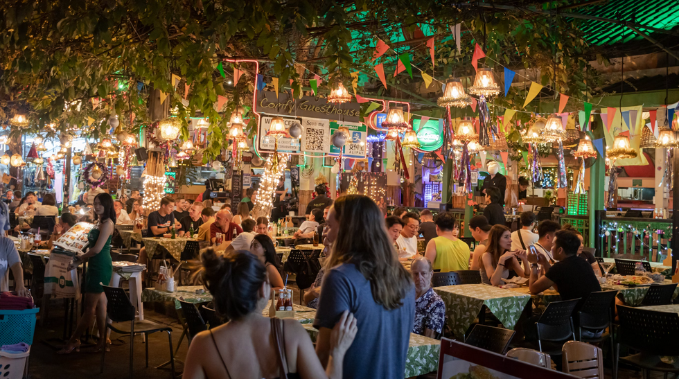 couple walking full restaurant with plants on the celling