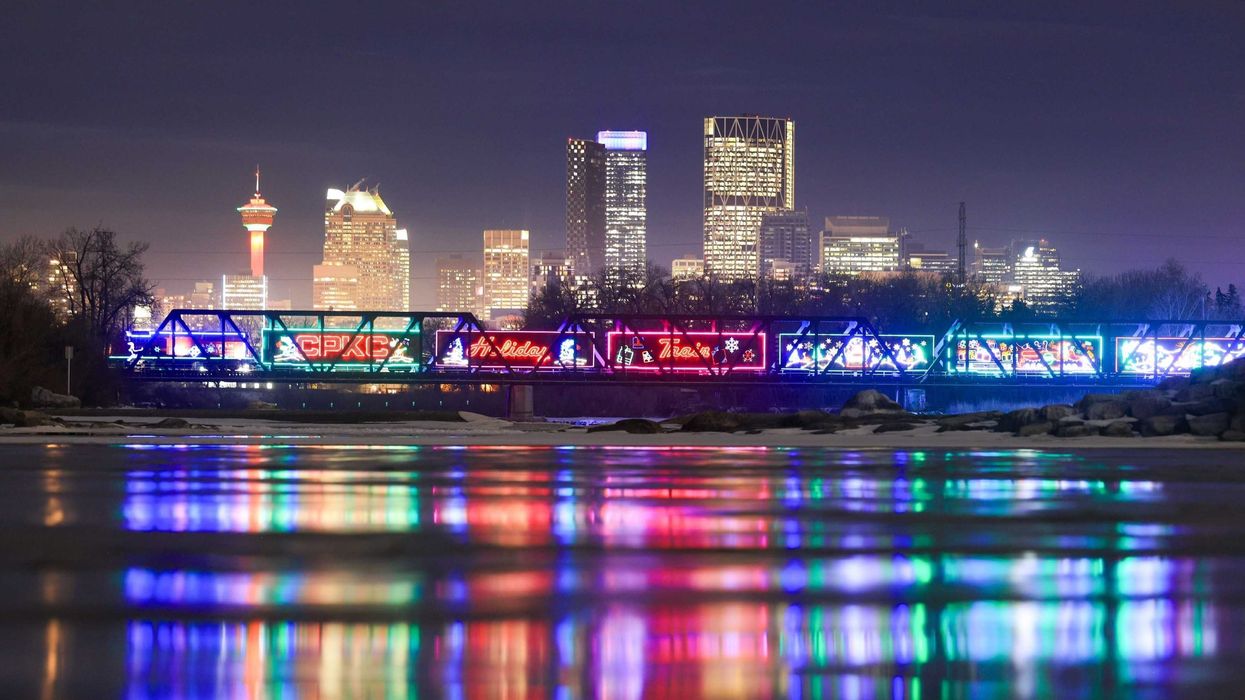 cpkc holiday train on a bridge with calgary skyline behind it
