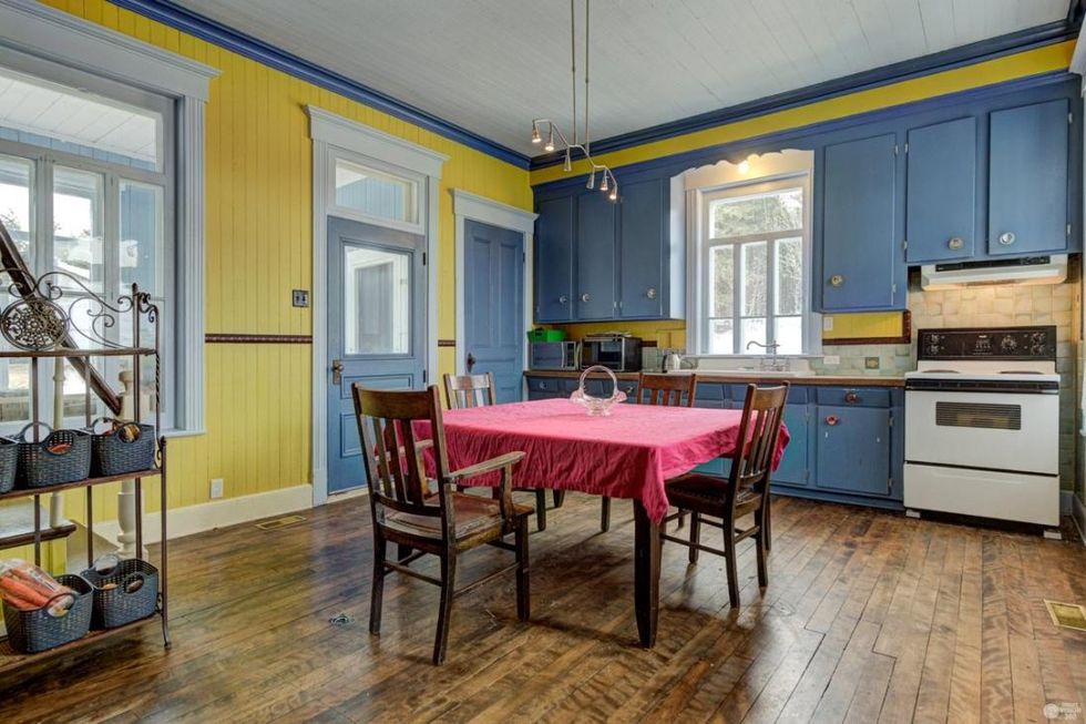 Cuisine avec murs jaunes et armoires bleues.