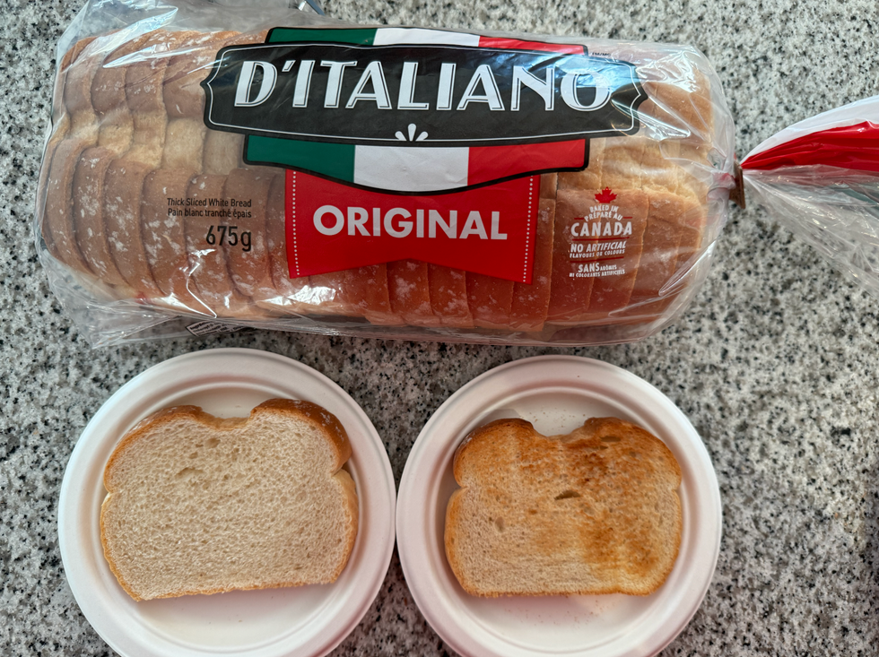 D'Italiano bread loaf with a slice on a white plate and another slice toasted on another plate.