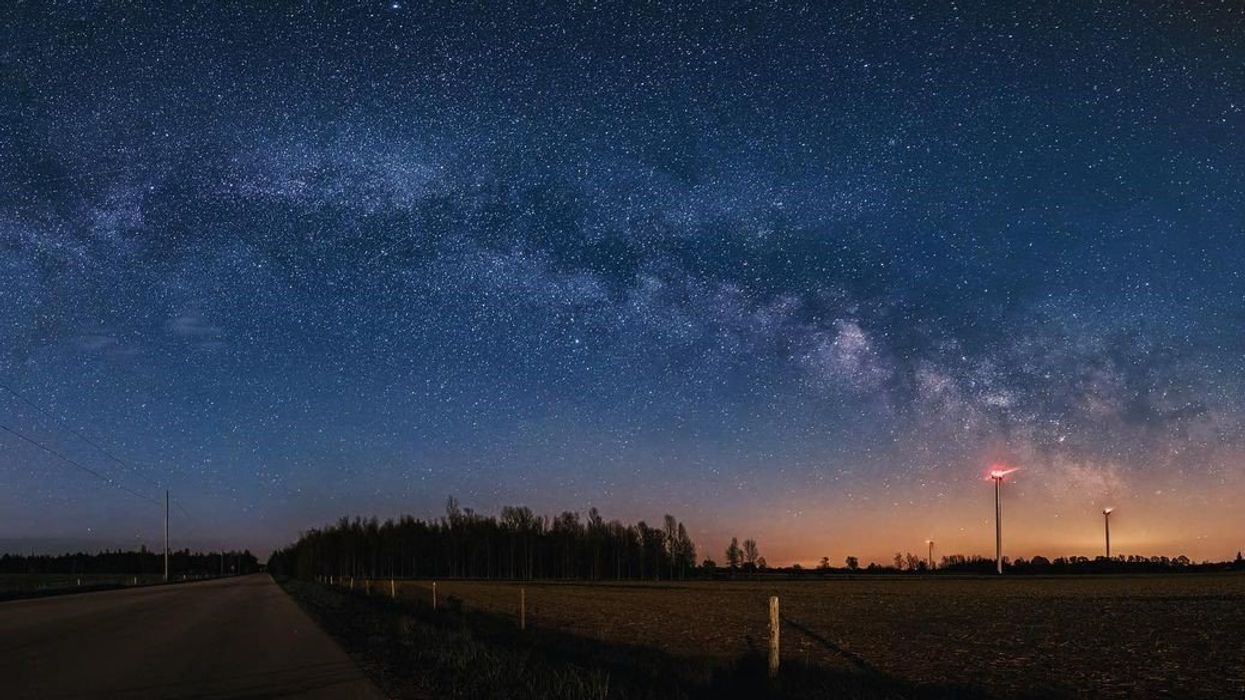 dark blue night sky with stars above a road and field at ontario's bruce peninsula national park