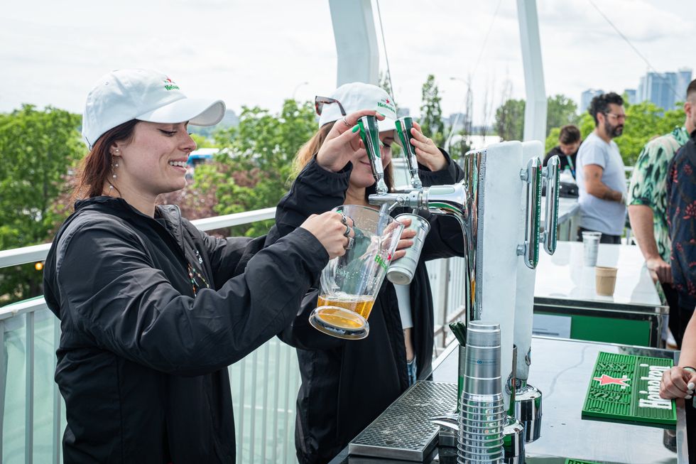 De jeunes femmes servant de la bi\u00e8re Heineken pression lors d'un \u00e9v\u00e9nement en plein air.