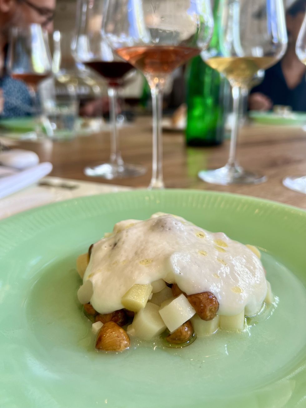 des asperges blanches coup\u00e9es en d\u00e9s avec des noisettes, napp\u00e9es une mousse dans une assiette verte.