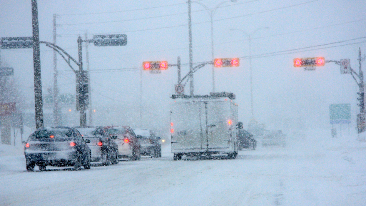 Des automobilistes attendent à un feu rouge dans une tempête de neige.