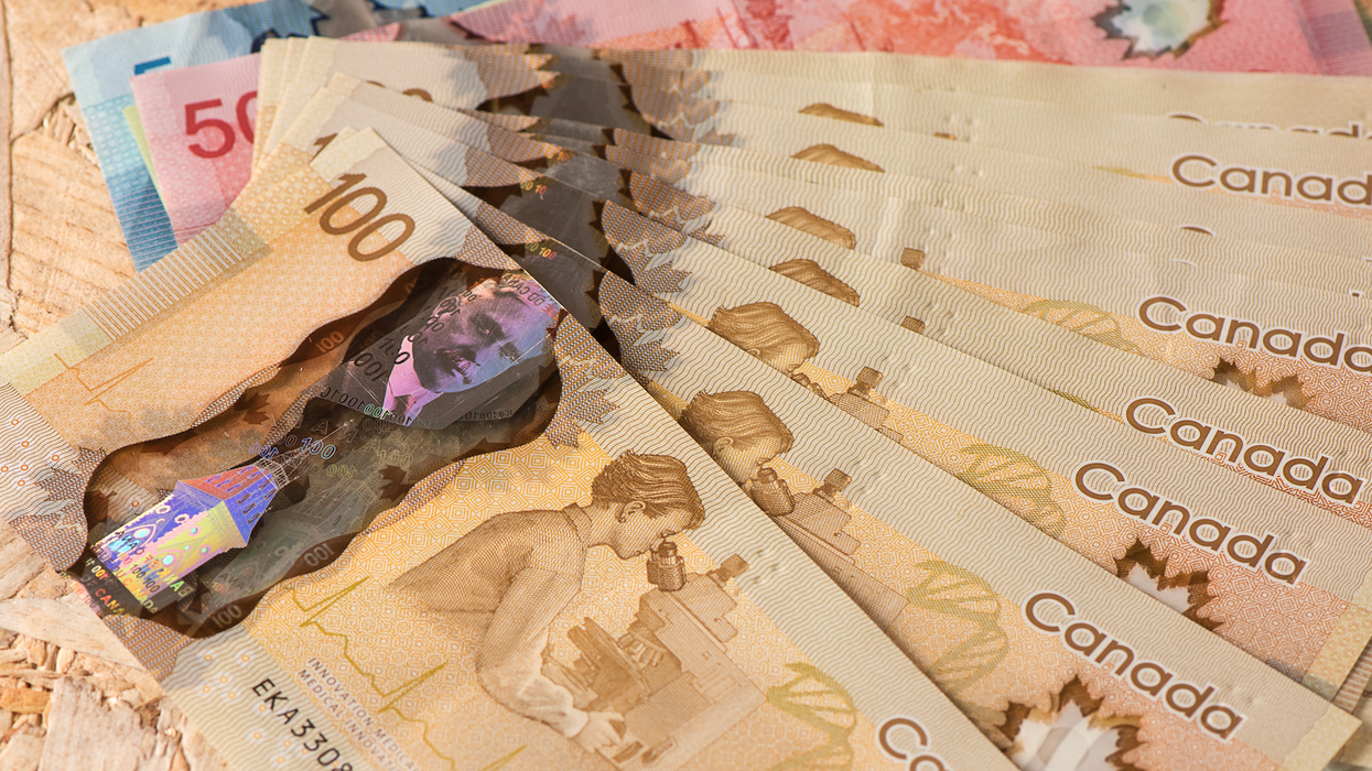 Des billets d'argent placés en éventail sur une table en bois.