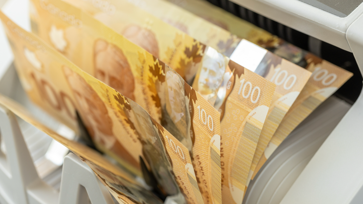 Des billets de 100 $ sortent d'une machine pour compter de l'argent.