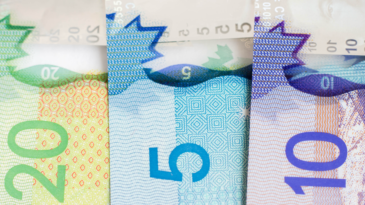 Des billets de 20 $, 10 $ et 5 $ alignés et étalés sur une surface plane en gros plan.