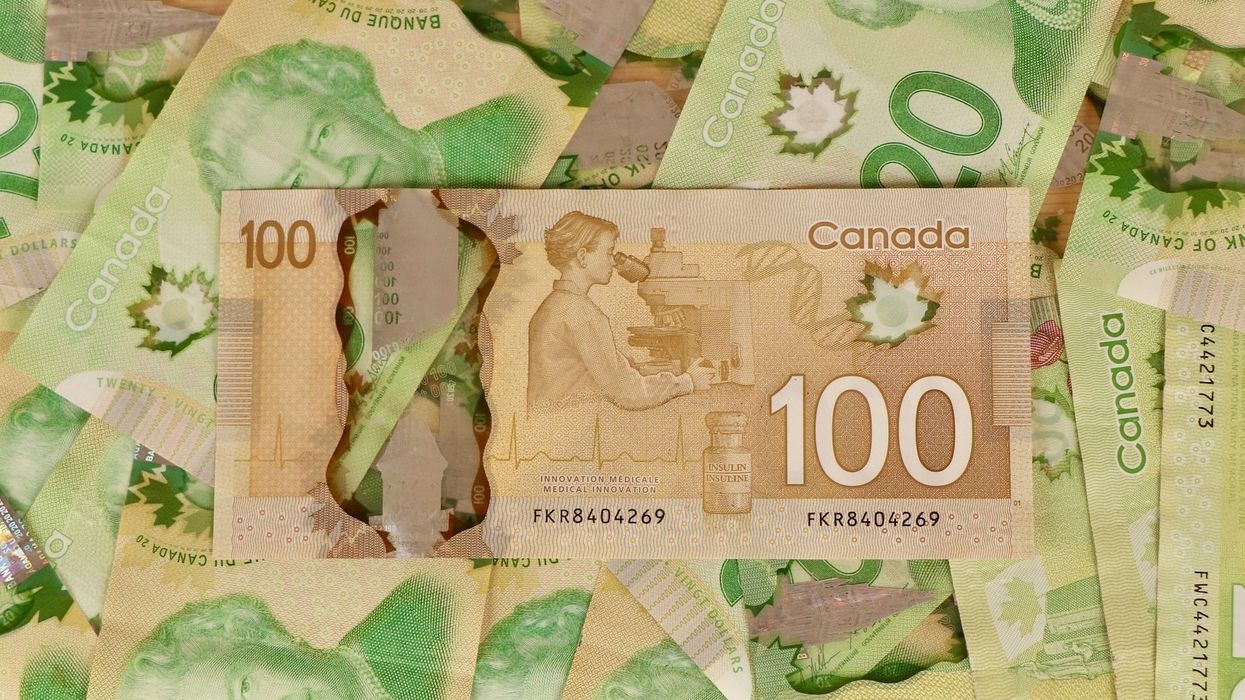 Des billets de 20 $ étalés sur une surface plane avec un 100 $ par-dessus.