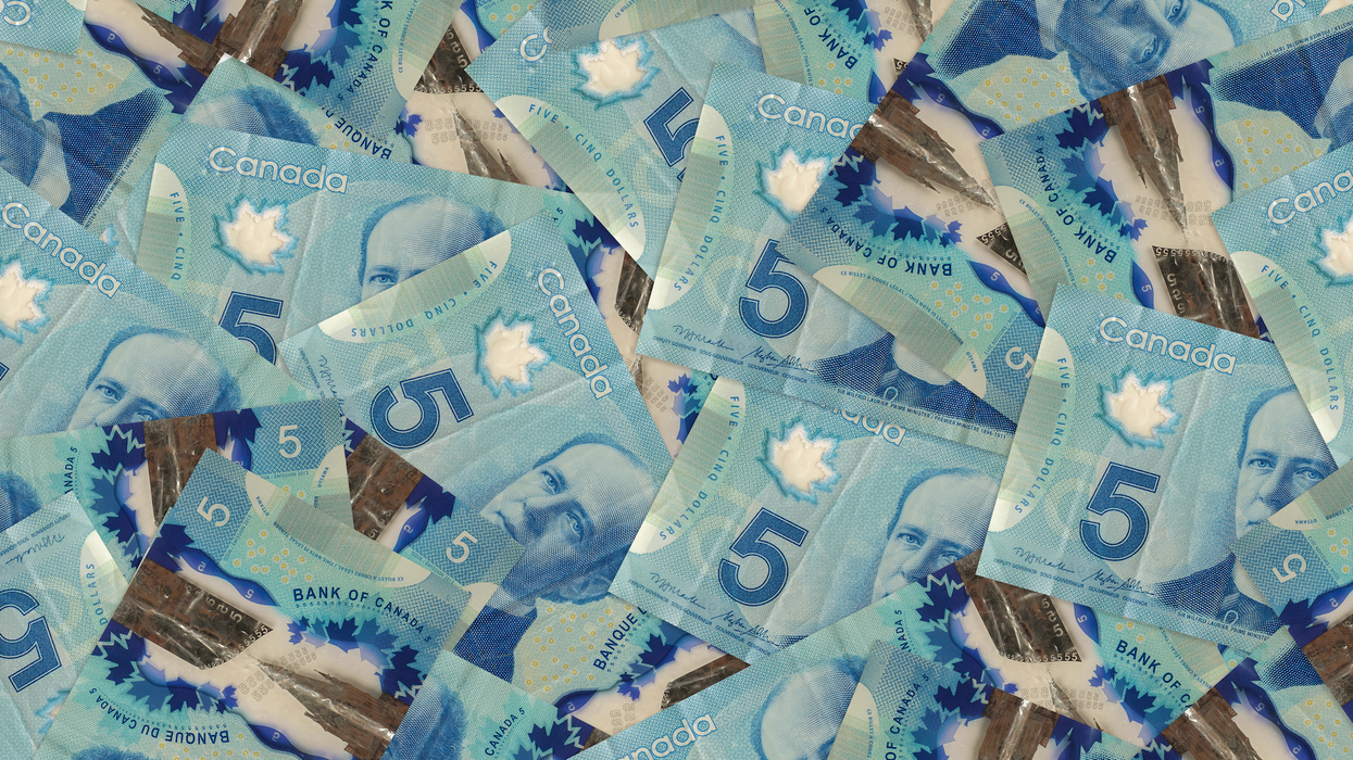 Des billets de 5 $ étalés sur une surface plane.