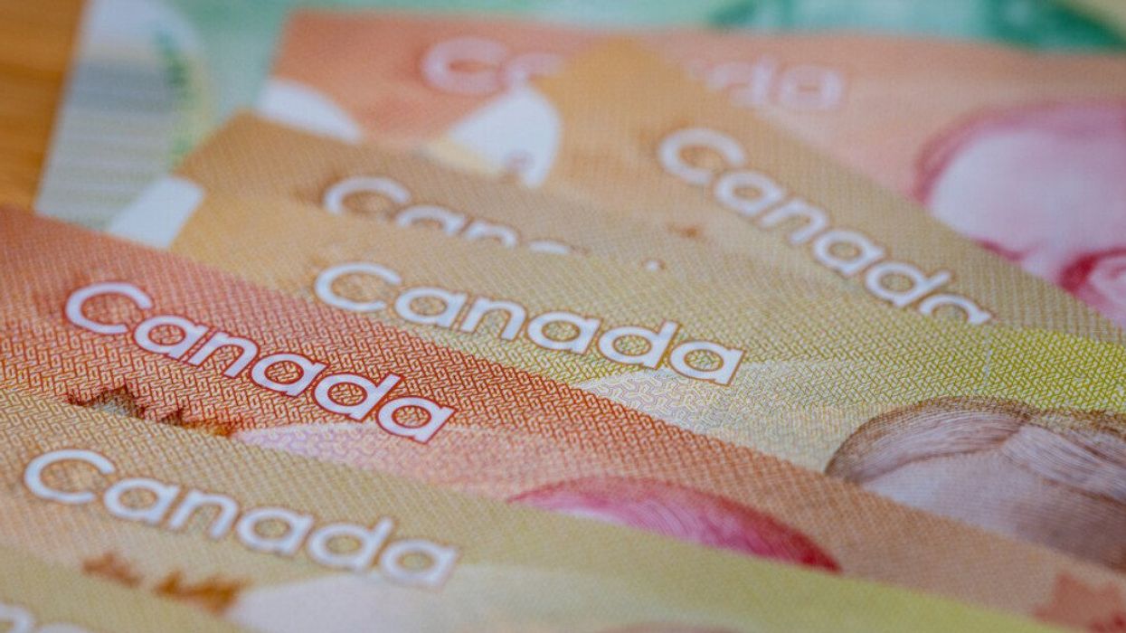 Des billets de 50 $ et 100 $ étalés sur une table en bois.