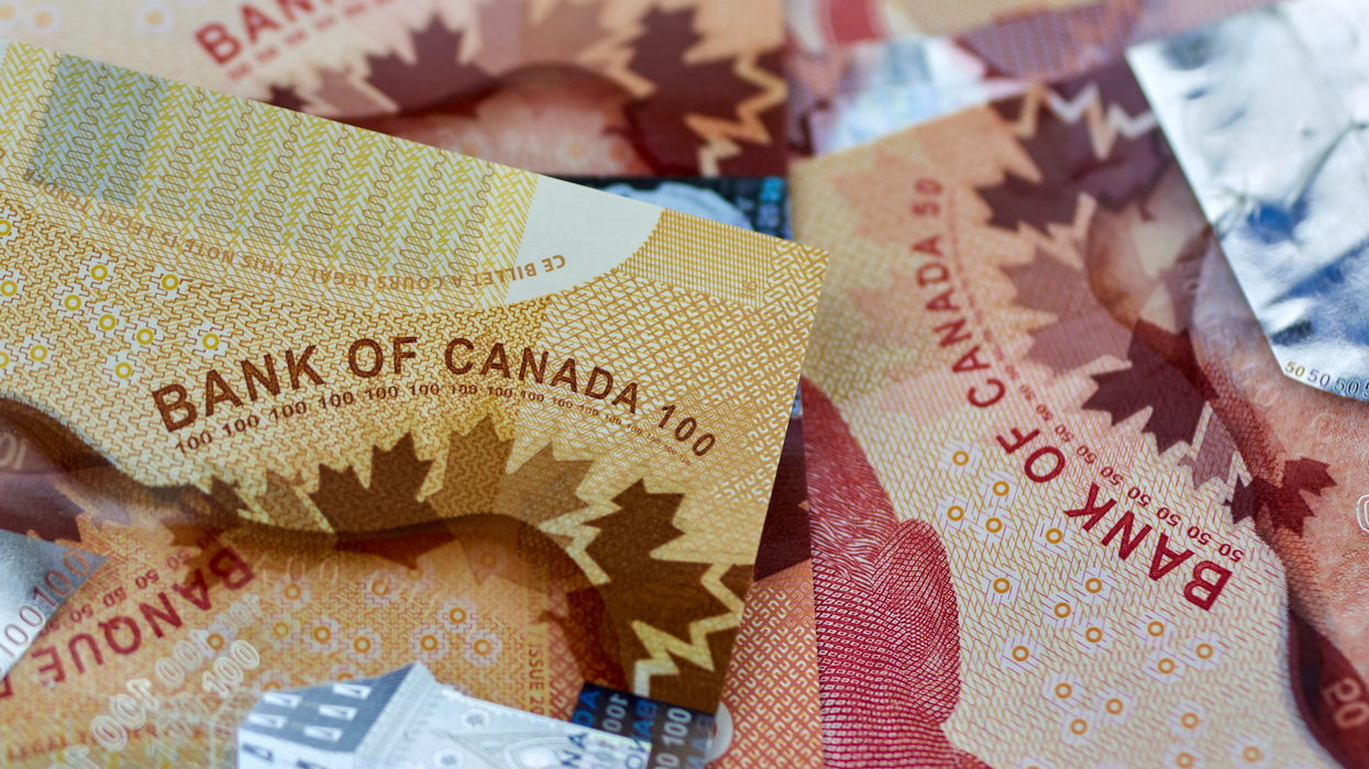 Des billets de 50 $ et 100 $ sont éparpillés sur une surface plane.