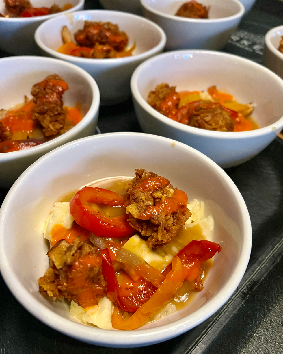 Des bols de poutine avec des morceaux de poulet croustillants et des lani\u00e8res de poivrons.