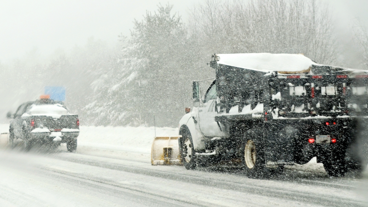 Des camions de déneigement circulent sur une route enneigée.
