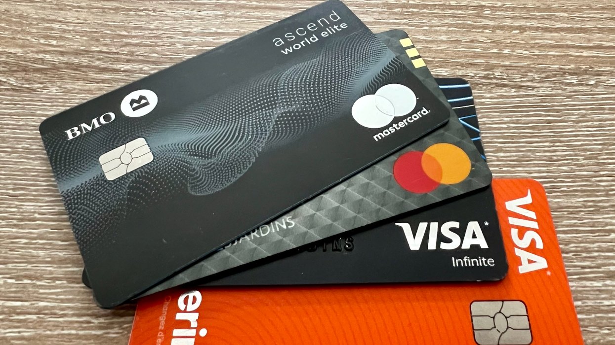 Des cartes de crédit noir, grise et orange sont placées en éventail sur une table.