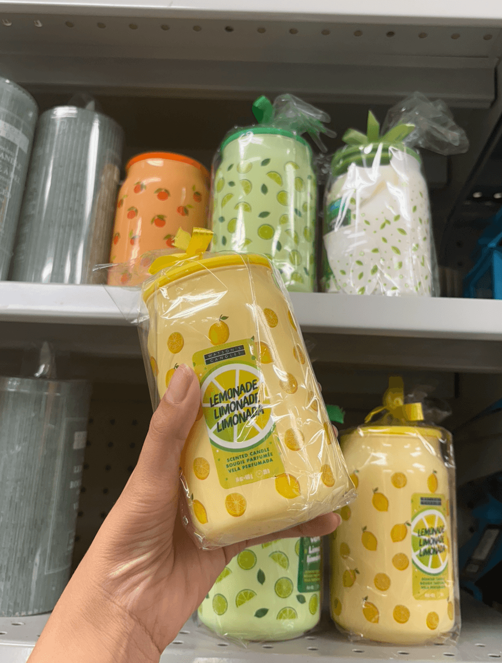 Des chandelles parfum\u00e9es d\u00e9cor\u00e9es de citrons, de limes et d'oranges sont pr\u00e9sent\u00e9es sur une \u00e9tag\u00e8re.