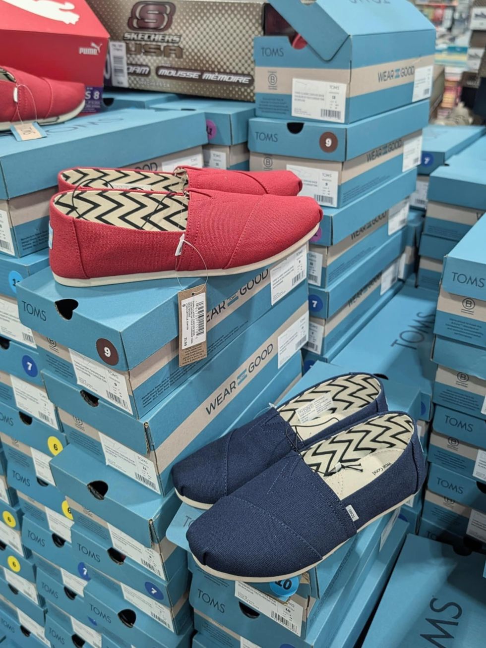 Des chaussures pour femme rouges et bleues de marque TOMS vendues dans le rayon des v\u00eatements chez Costco.