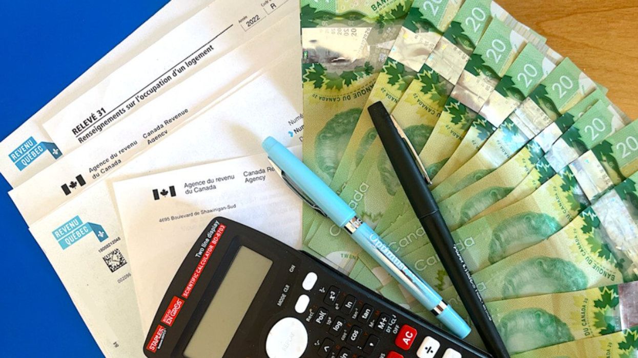Des documents d'impôts sont placés sur une table avec des billets de 20 $, des crayons et une calculatrice.