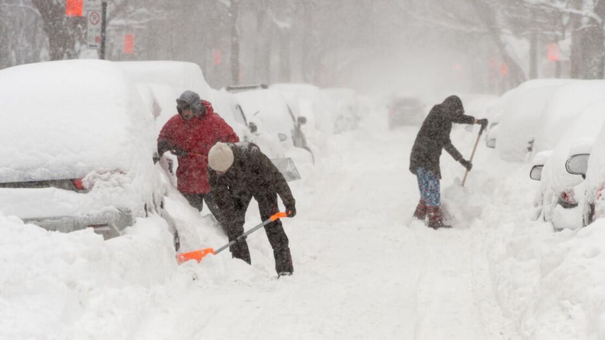 Des gens qui déneigent leur voiture lors d'une tempête.