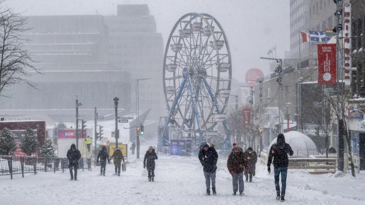 Des gens qui marchent dans la rue lors d'une tempête de neige à Montréal.