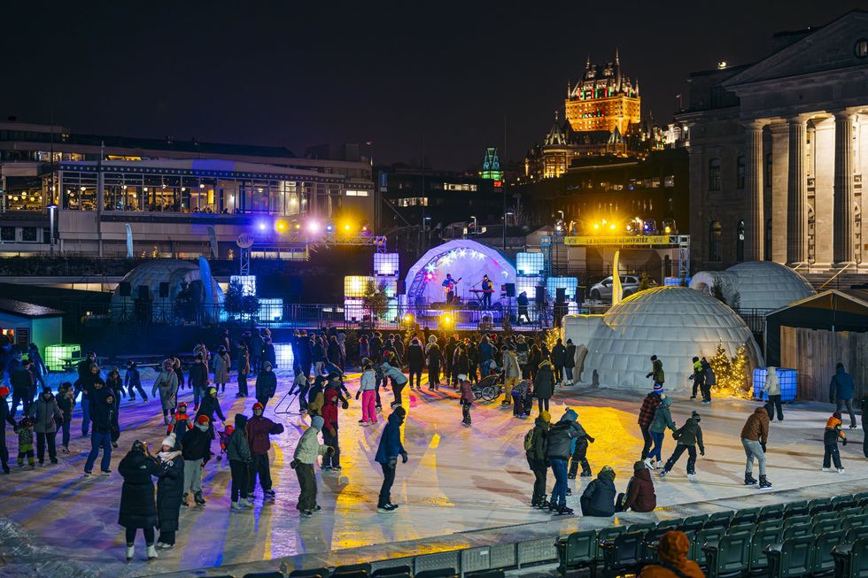 Des gens qui patinent sur la Discoglace du Port de Qu\u00e9bec illumin\u00e9e.