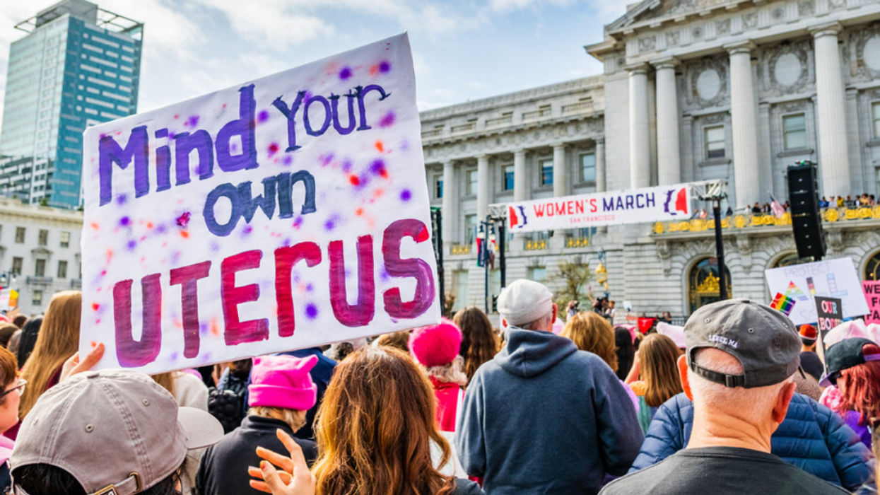 Des gens tiennent des pancartes à une manifestation sur le droit à l'avortement à San Francisco : Mind your own uterus (Occupe-toi de ton propre utérus) et Women's march (la marche des femmes).