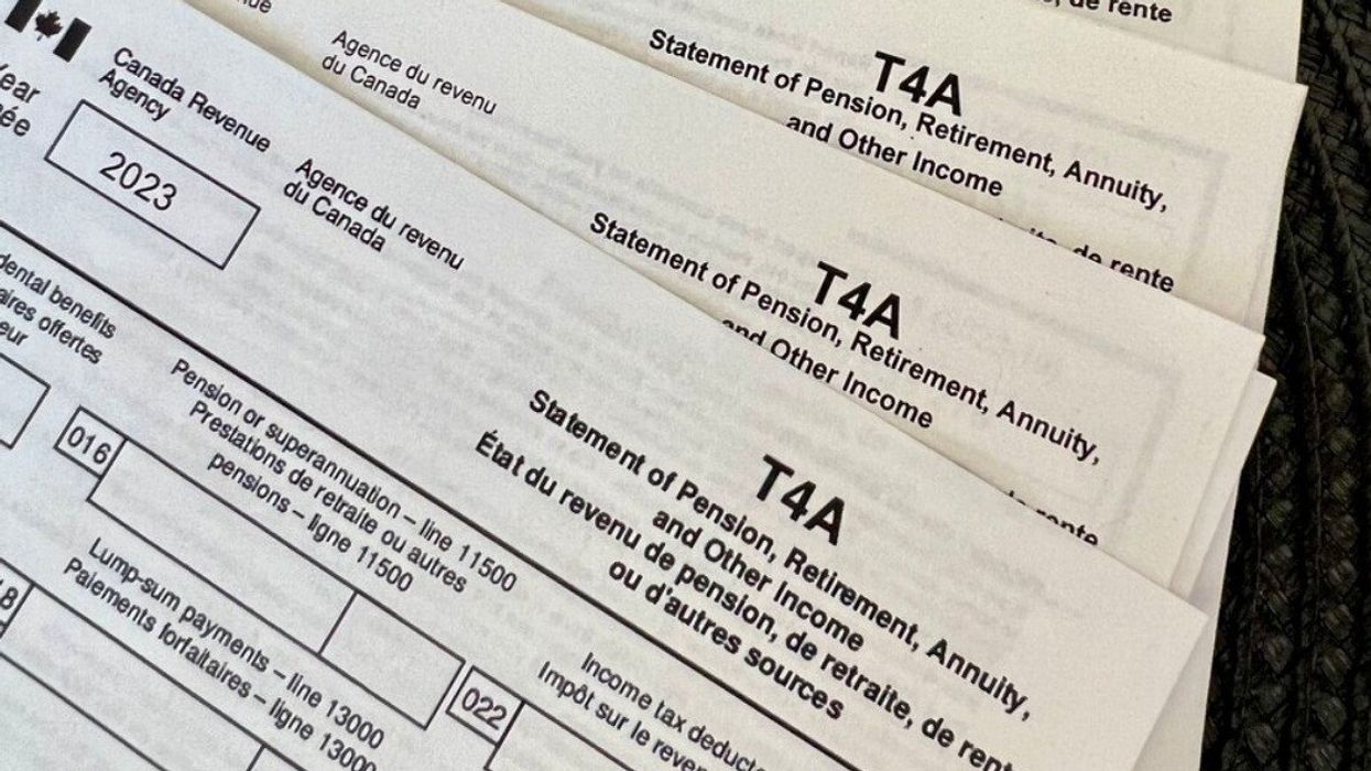 Des papiers d'impôts, de relevés TA4 de l'Agence du Revenu du Canada sont étalés sur une surface noire.
