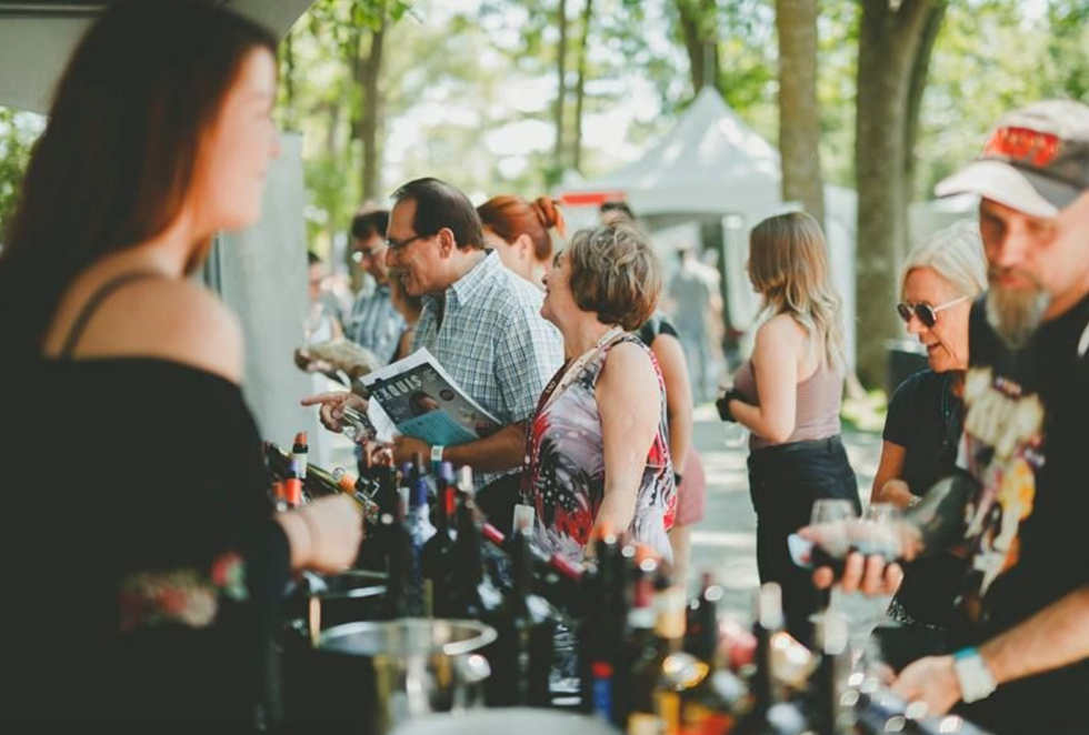 Des personnes devant un kiosque de vins au festival Vins et Histoire de Terrebonne.