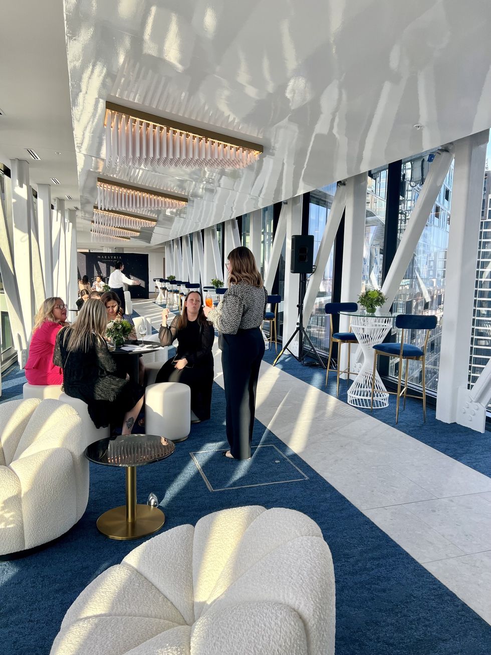 Des personnes discutent au centre d'une passerelle-loge vitr\u00e9e.