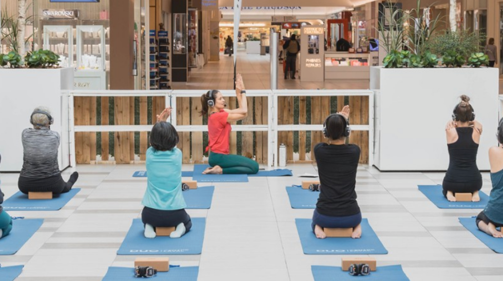 Des personnes font du yoga dans un centre commercial.