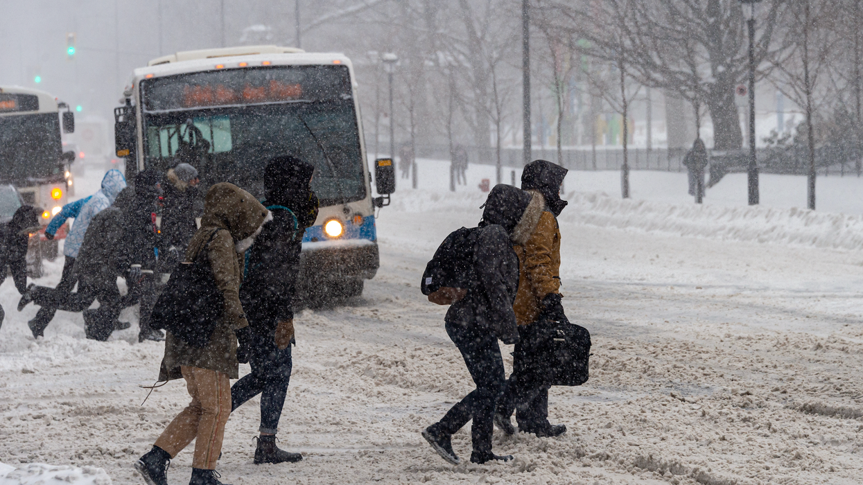 Des personnes marchent dans la neige devant des autobus de STM.
