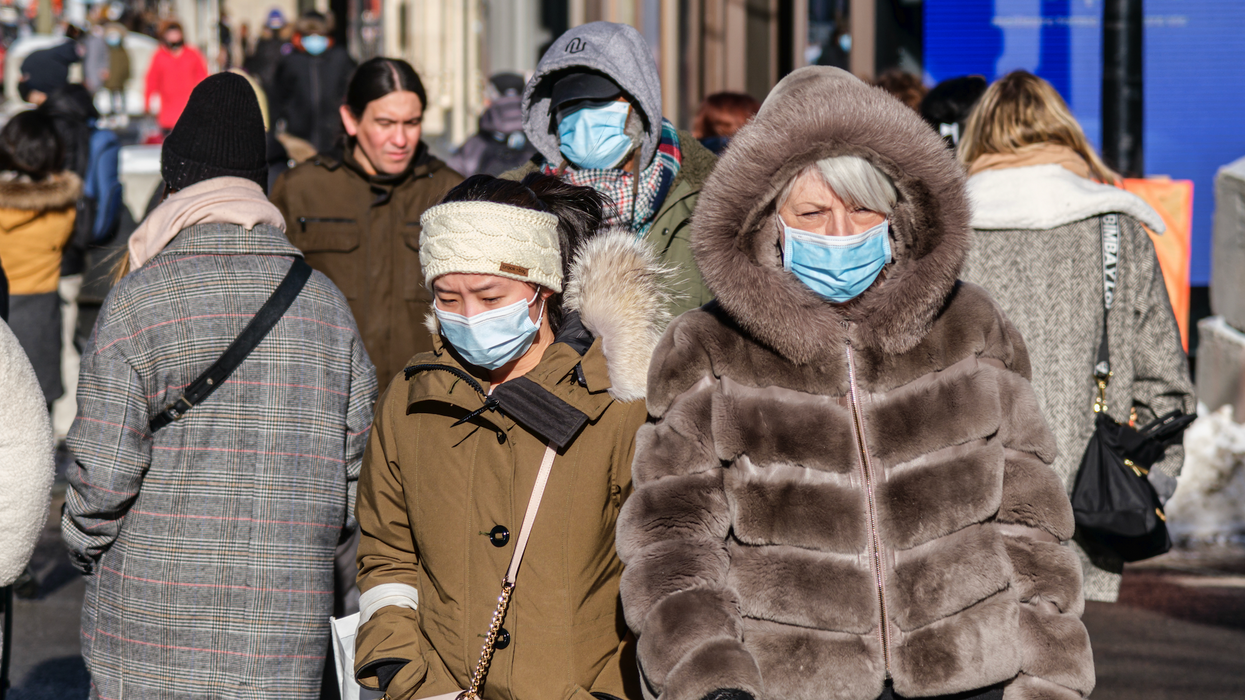 Des personnes marchent sur une rue bondée à Montréal tout en portant des masques bleus.