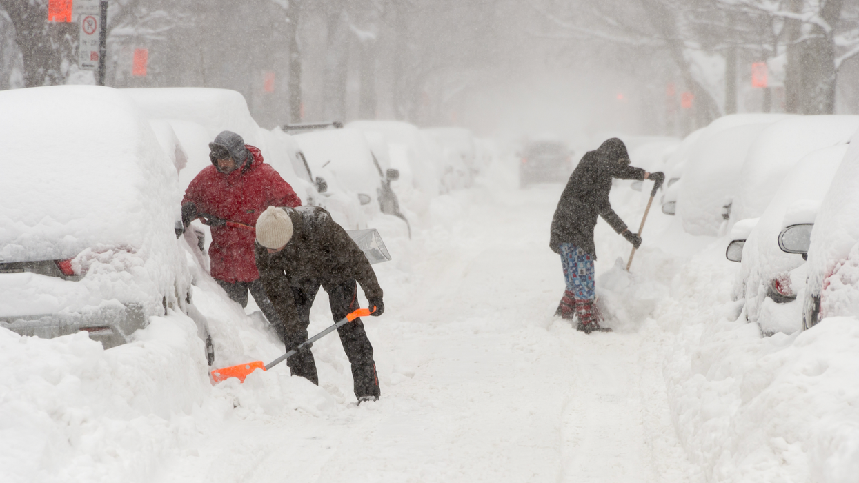 Des personnes sont en train de pelleter de la neige autour de leur véhicule.