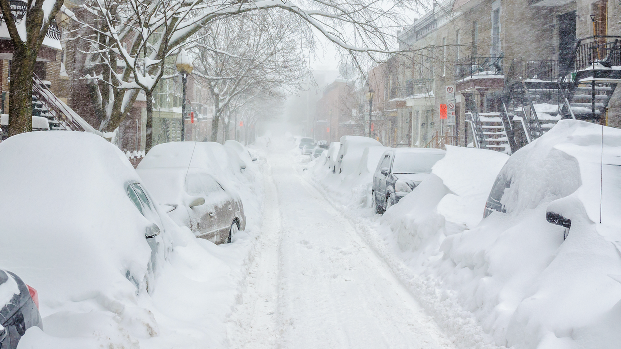 Des véhicules sont ensevelis sous la neige dans une rue à Montréal.