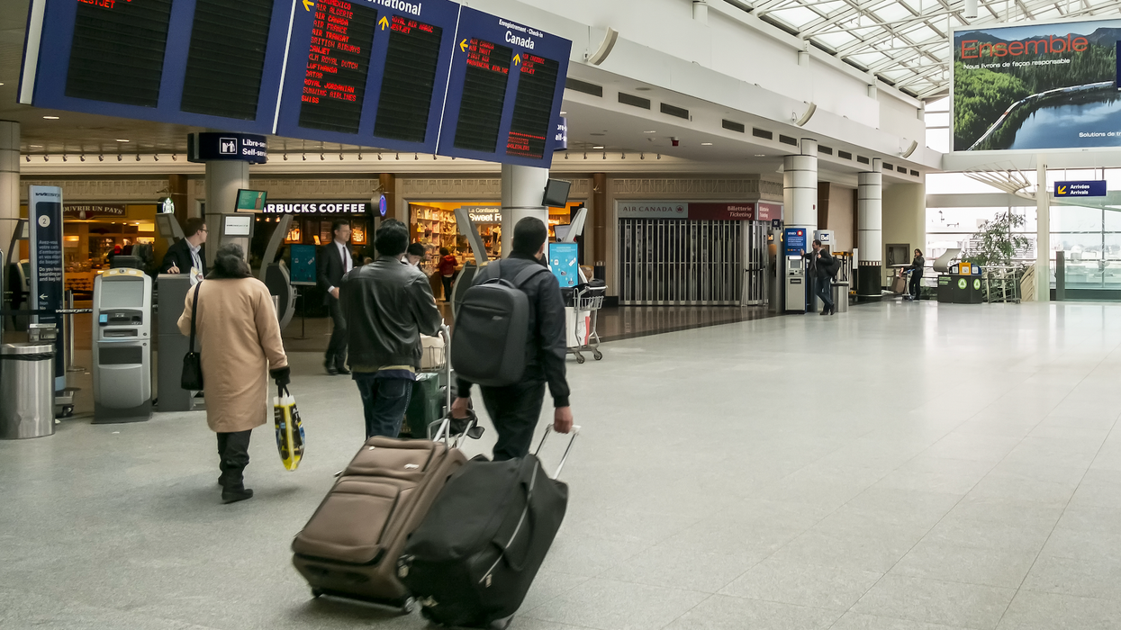 Des voyageurs circulent à l'aéroport de Montréal avec leur valise.