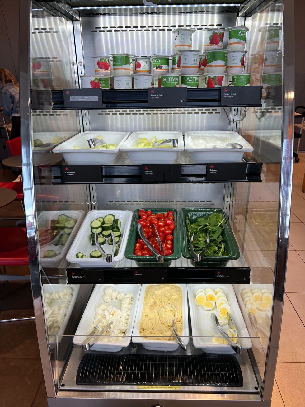 Des yogourts, des l\u00e9gumes, des \u00e9pinards, des oeufs durs, du hummus et du fromage \u00e0 la cr\u00e8me sont servis dans un frigo ouvert.
