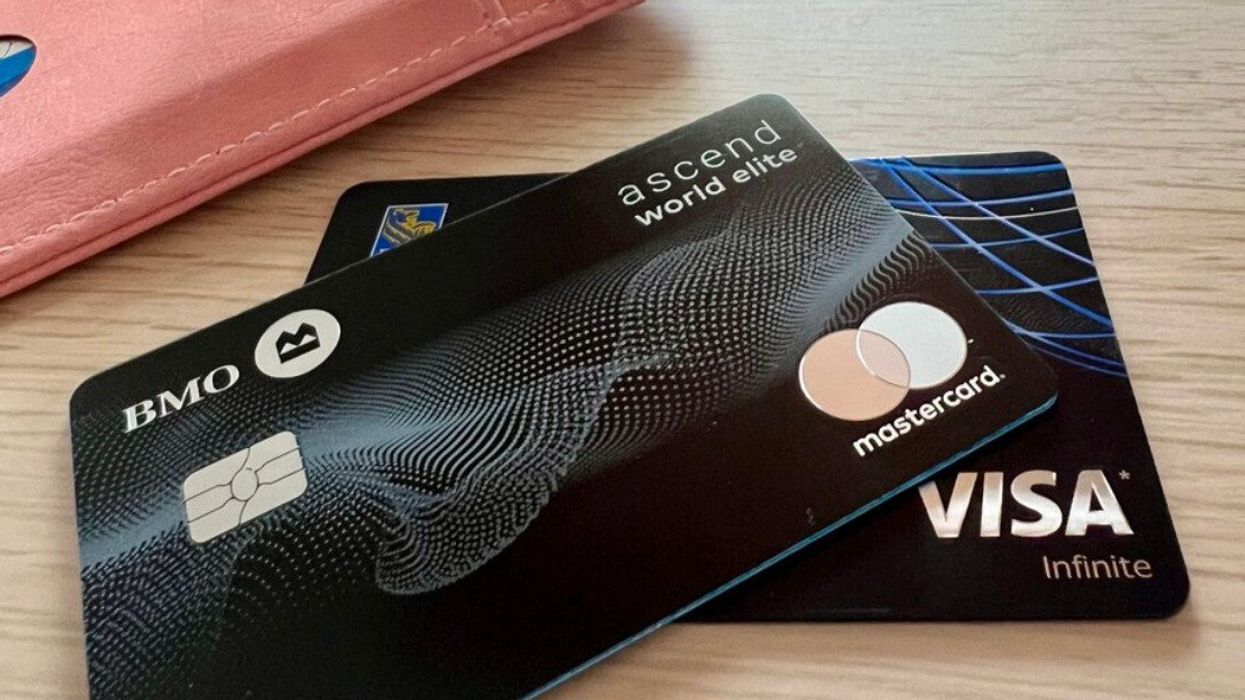 Deux cartes de crédit noires sont placées en éventail à côté d'un porte-cartes rose sur une table.