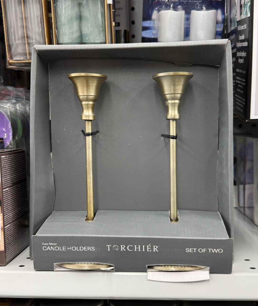 Deux chandeliers en m\u00e9tal dor\u00e9 expos\u00e9s dans leur emballage sur les tablettes du Dollarama.