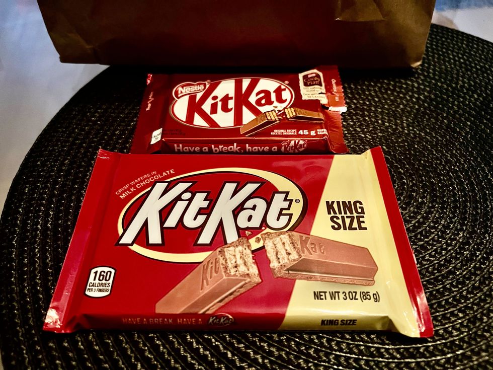 Deux emballages de chocolat KitKat sont plac\u00e9s sur un napperon rond noir.