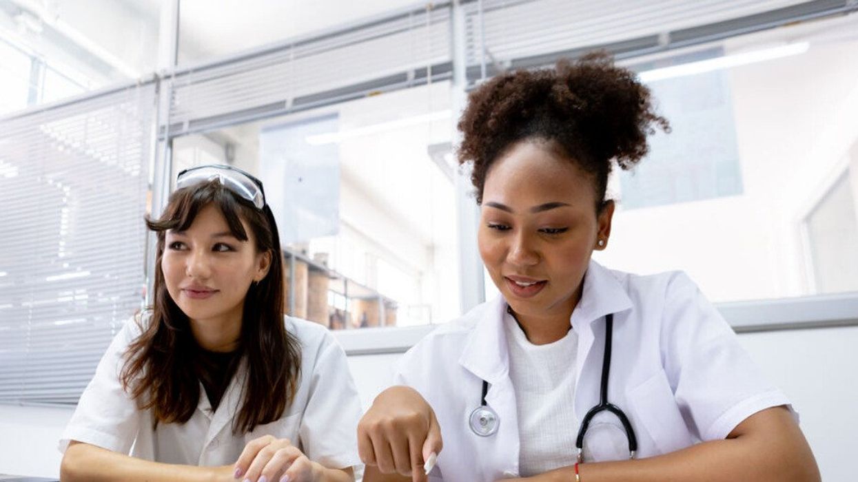 Deux femmes vêtues d'un habit de travail blanc sont assises dans un bureau d'hôpital.