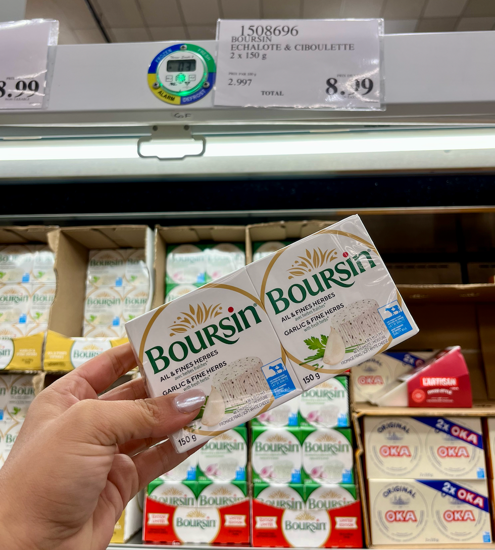 Deux fromages Boursin \u00ab Ail et fines herbes \u00bb dans une main au Costco.