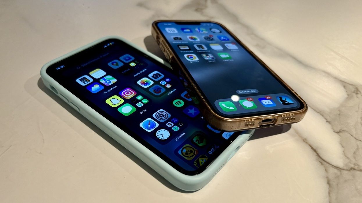 Deux iPhone sont étalés sur une table blanche et grise.