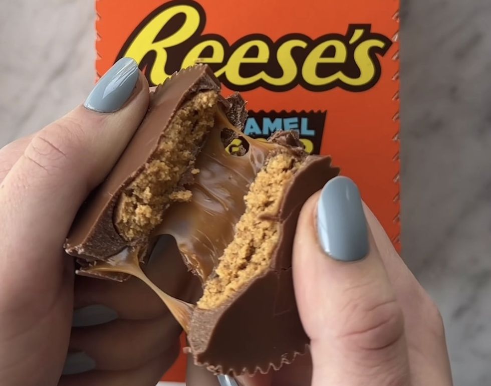 Deux mains qui s\u00e9parent un Reese's Big Cup avec Caramel.