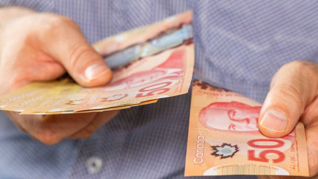 Deux mains qui tiennent des billets de 50 $ canadien.