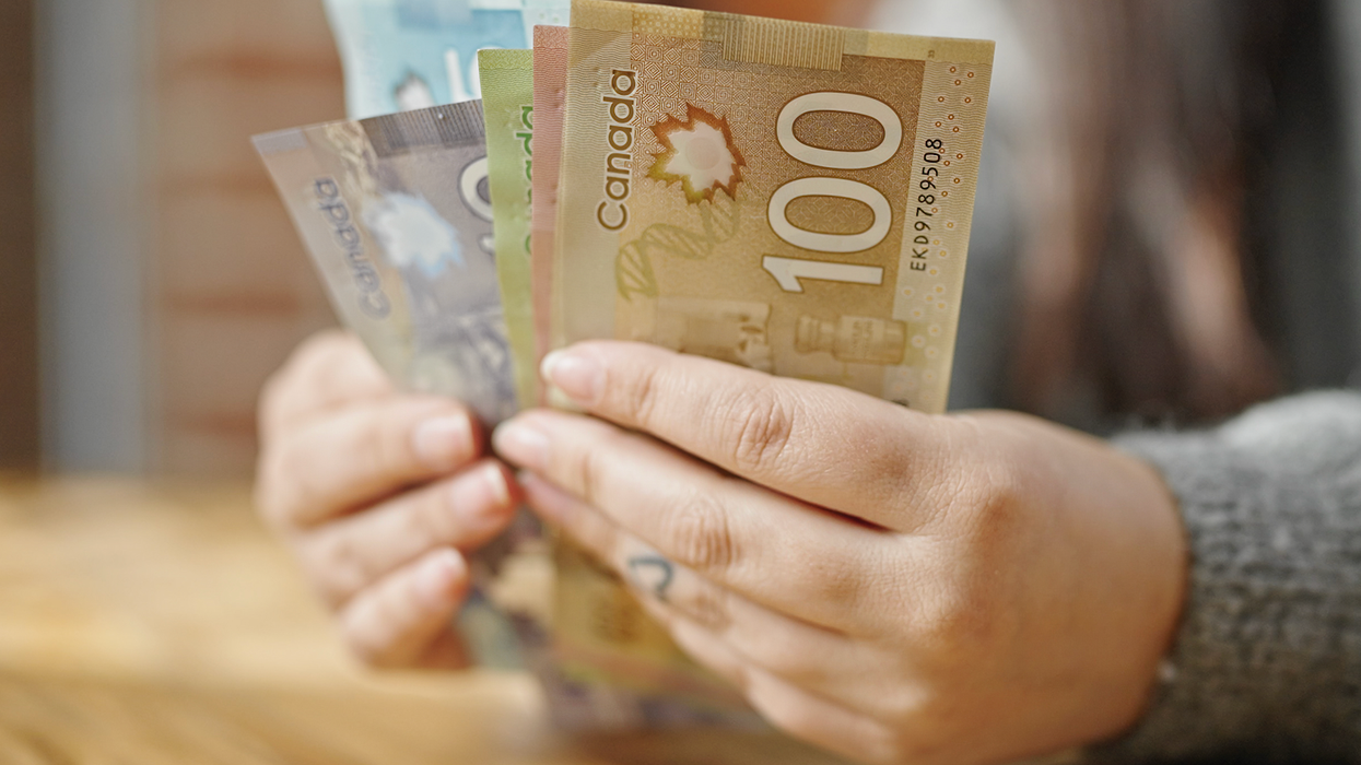 Deux mains tiennent des billets d'argent placés en éventail.