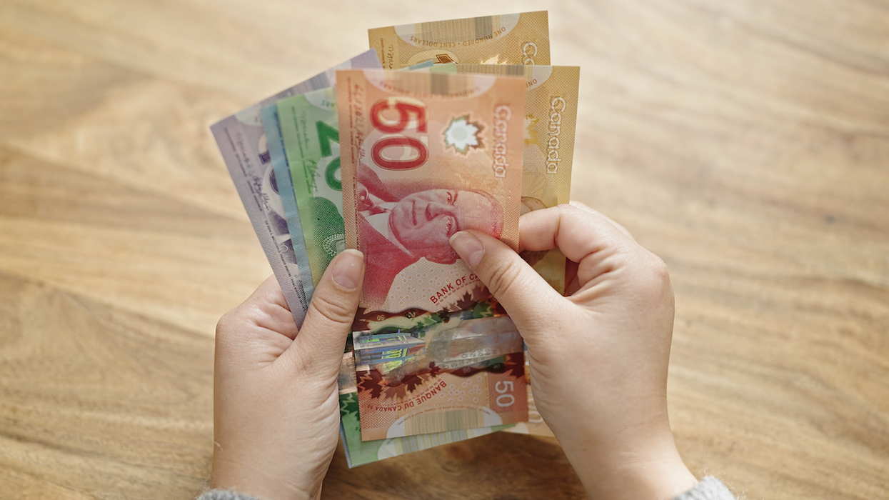 Deux mains tiennent des billets de 100 $, 50 $, 20 $, 10 $ et 5 $.