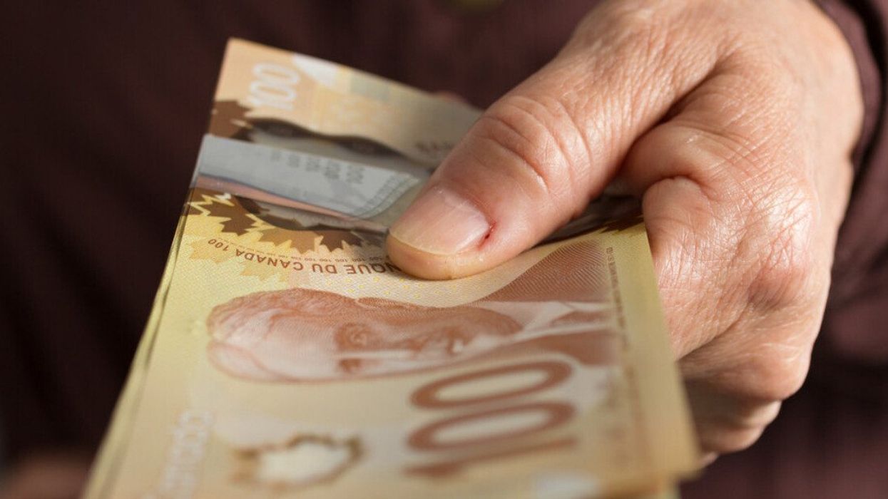 Deux mains tiennent des billets de 100 $.