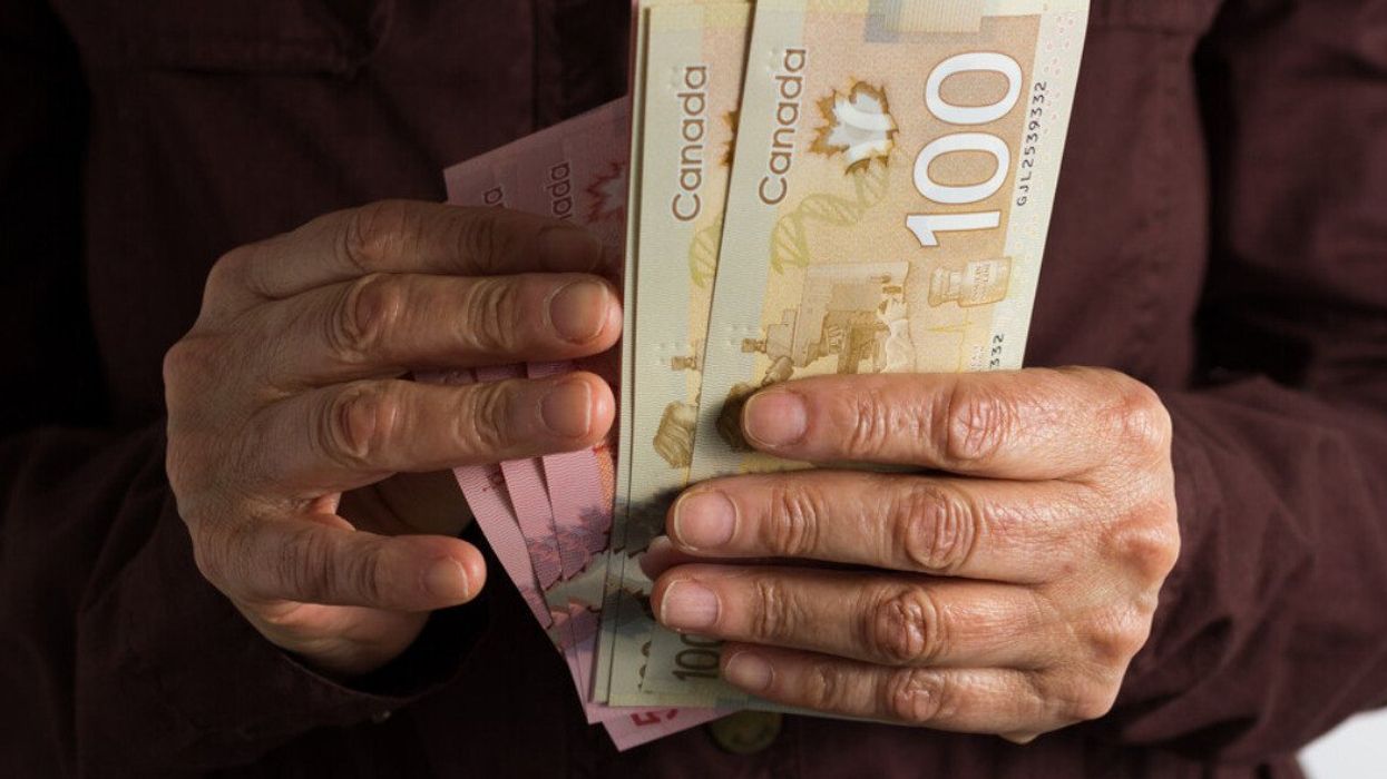Deux mains tiennent des billets de 50 $ et 100 $ canadien.