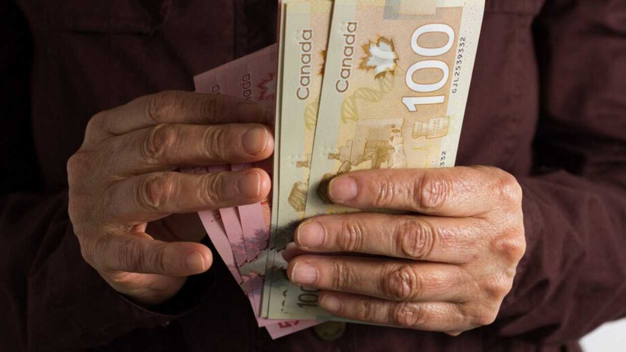 Deux mains tiennent des billets de 50 $ et 100 $ canadien.