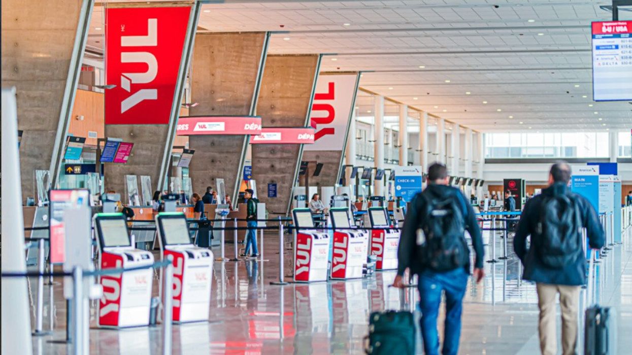 Deux personnes de dos transportent leur valise à l'aéroport de Montréal.